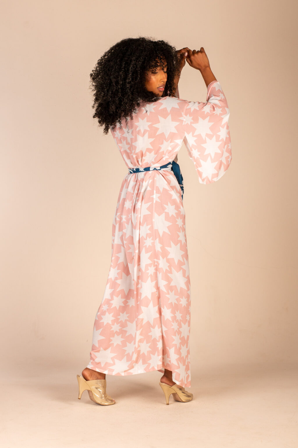 Mulher morena usando kimono longo manga longa faixa de amarração na cintura estampa exclusiva rosa com estrelas brancas conforto praticidade elegância kimono Miss Gion maria sanz kimono quimono