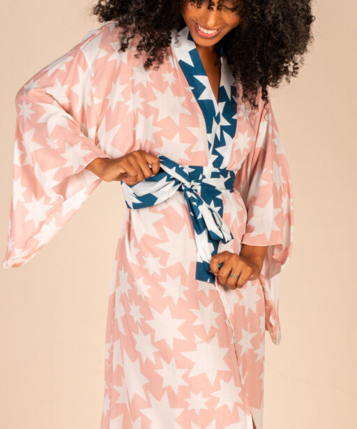 Mulher morena usando kimono longo manga longa faixa de amarração na cintura estampa exclusiva rosa com estrelas brancas conforto praticidade elegância kimono Miss Gion maria sanz kimono quimono