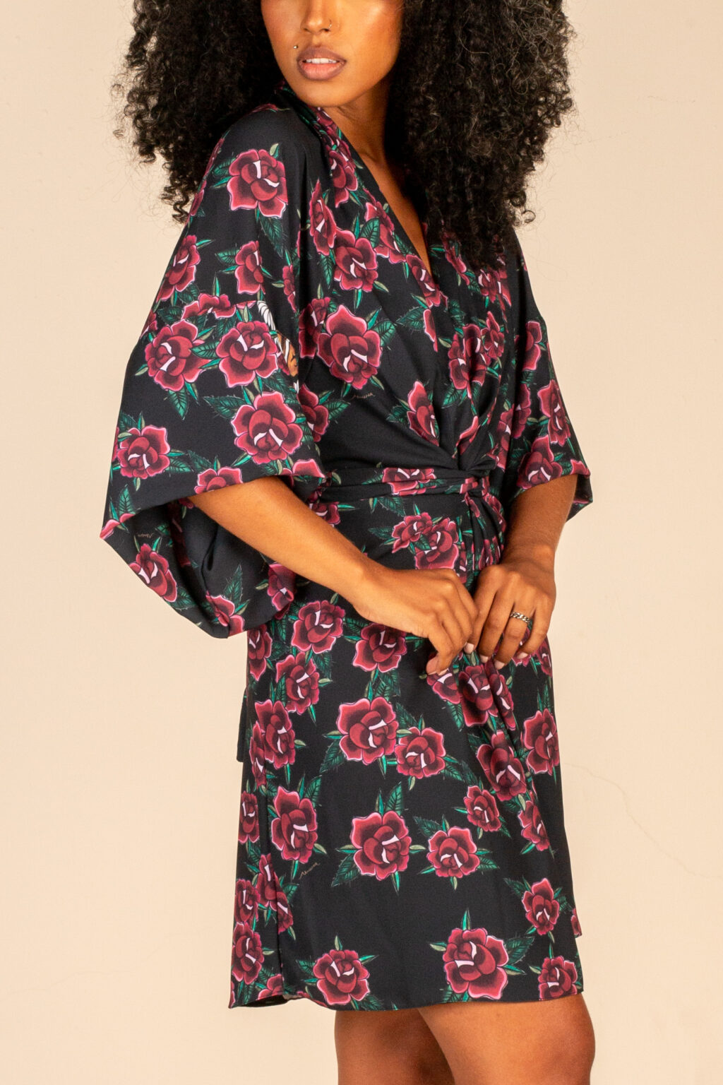 Mulher morena usando kimono curto manga curta com faixa de amarração na cintura estampa exclusiva preta com rosas e tigre conforto praticidade elegância terceira peça kimono Carmem maria sanz kimono quimono