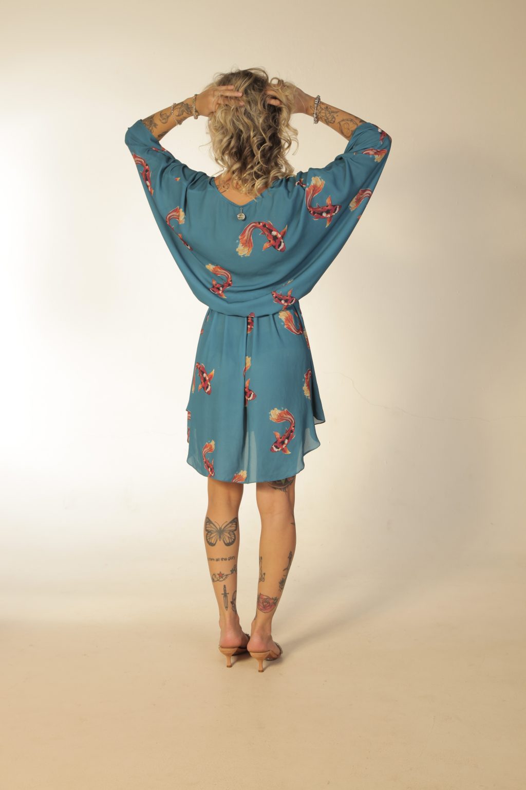 Mulher loira usando um vestido curto manga curta decote v com elástico e faixa na cintura estampa exclusiva carpas laranja praticidade elegância conforto kimono lovers maria sanz kimono quimono
