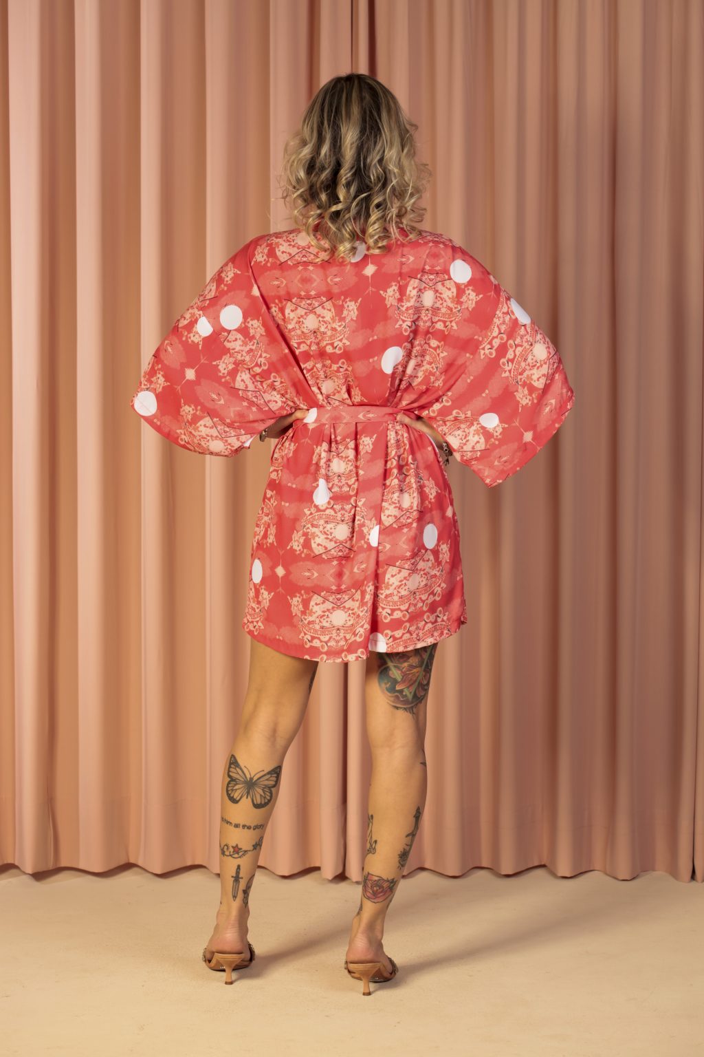 Mulher loira usando um kimono curto manga curta faixa para amarração na cintura estampa exclusiva terceira peça conforto praticidade elegância leveza maria sanz kimono