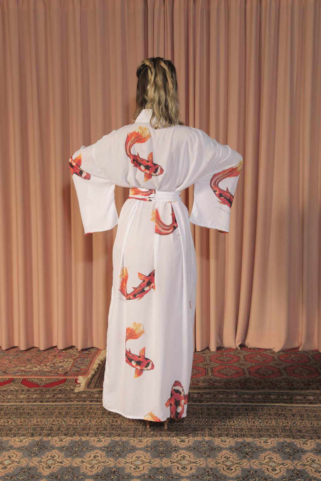Mulher loira usando um kimono longo manga longa faixa na cintura estampa exclusiva branco com carpas leveza conforto praticidade maria sanz kimono quimono
