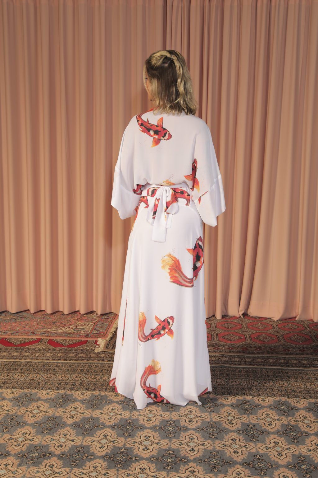 Mulher loira usando um vestido longa manga curta amarração na cintura estampa exclusiva de carpas elegância conforto leveza praticidade maria sanz kimono quimono