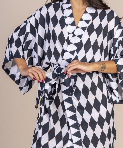 Mulher morena usando um kimono curto manga curta faixa para amarração na cintura estampa exclusiva losango preto e branco joker conforto praticidade elegância maria sanz kimono quimono