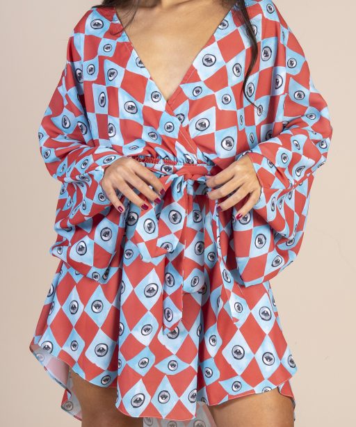 Mulher morena usando um vestido curto manga curta decote v com elástico e faixa na cintura estampa exclusiva losango azul e vermelho com olhos desenhados a mão praticidade elegância conforto joker maria sanz kimono quimono