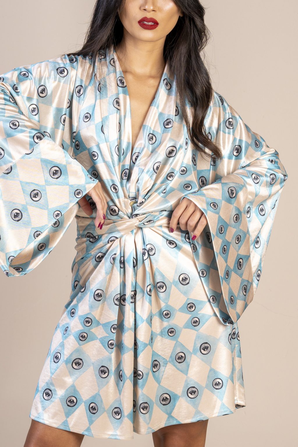 Mulher morena usando um vestido curto manga longa amarração na cintura estampa exclusiva losango bege e azul com olhos desenhados a mão exclusivo conforto elegância praticidade maria sanz kimono quimono joker