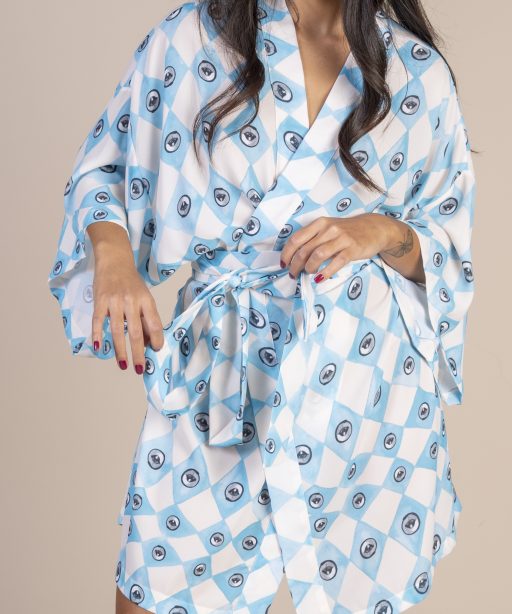 Mulher morena usando um kimono curto manga curta estampa exclusiva losango bege e azul com olhos desenhados a mão joker conforto praticidade elegância maria sanz kimono quimono