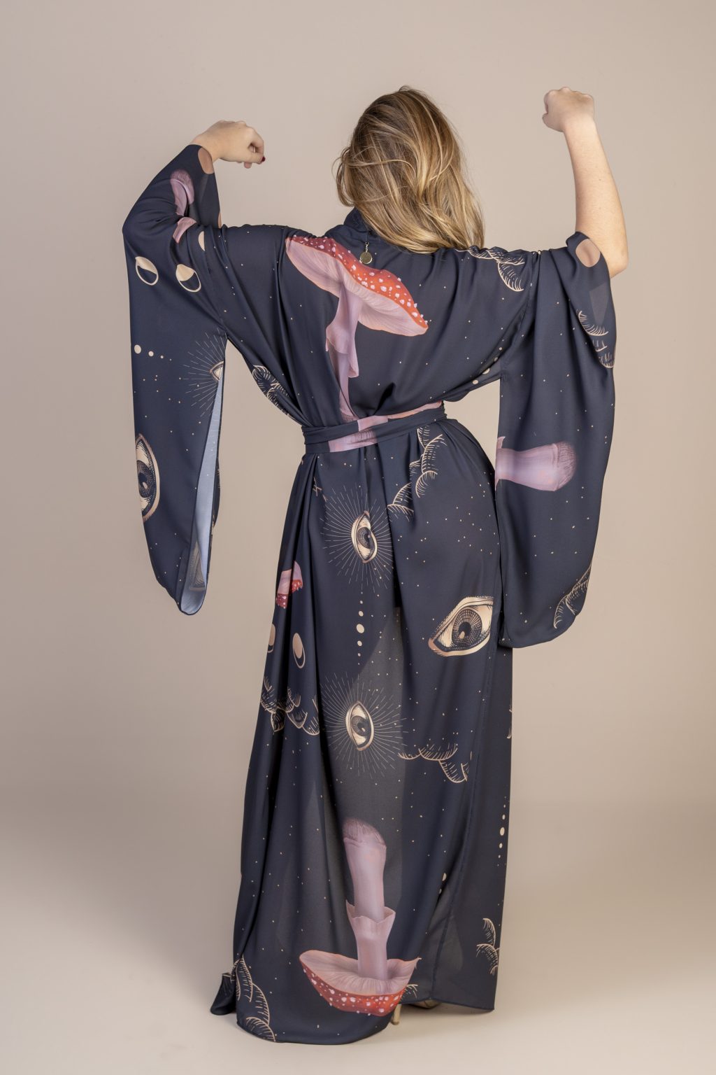 Mulher loira usando um kimono longo manga longo estampa exclusiva preto e cogumelos vermelhos com olhos desenhados a mão conforto praticidade elegância joker maria sanz kimono quimono
