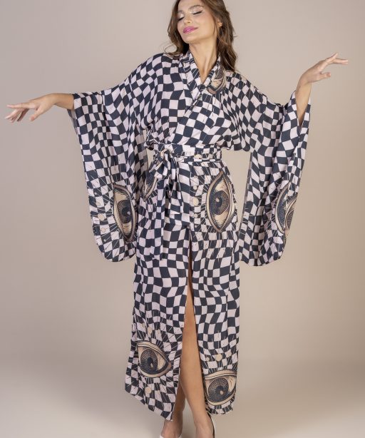 Mulher morena usando um kimono longo manga longa estampa de xadrez preto e bege com olhos grandes desenhados a mão faixa na amarração na cintura conforto praticidade elegância joker maria sanz kimono quimono