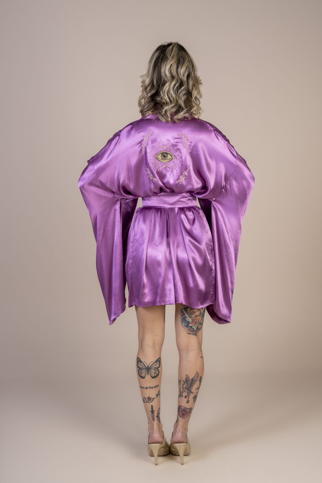 Mulher loira usando um kimono curto manga longa lilás de viscose com bordado nas costas faixa para amarração na cintura exclusivo praticidade elegância conforto maria sanz kimono quimono