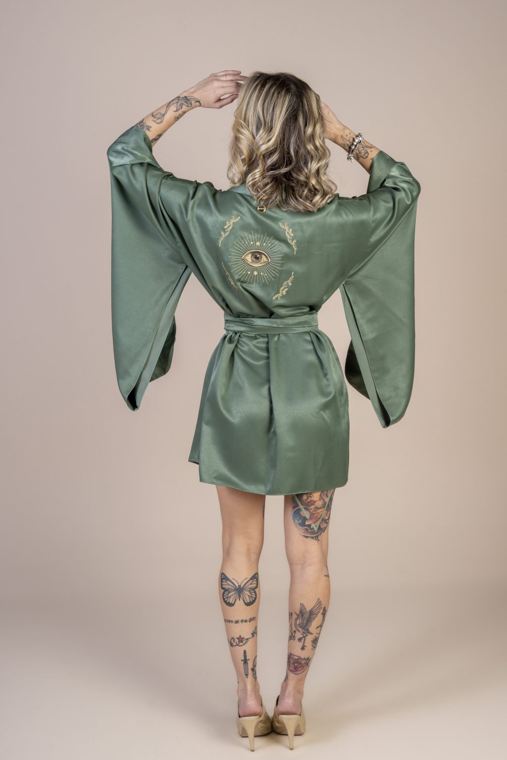 Mulher loira usando um kimono curto manga longa verde de viscose com bordado nas costas faixa para amarração na cintura exclusivo praticidade elegância conforto maria sanz kimono quimono