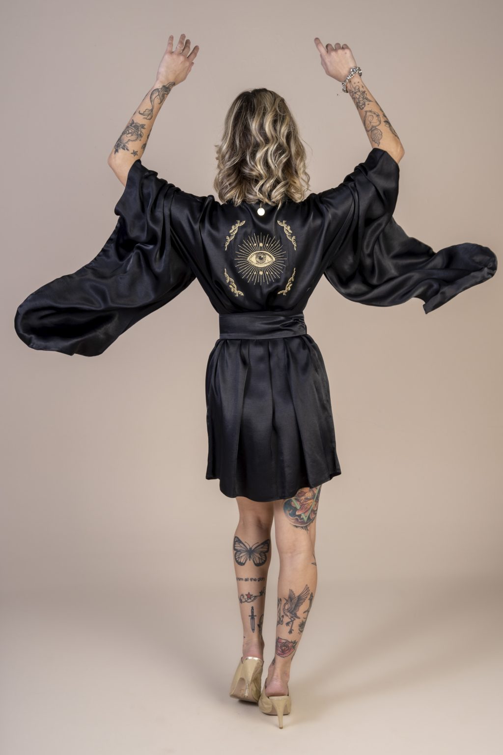 Mulher loira usando um kimono curto manga longa preto de viscose com bordado nas costas faixa para amarração na cintura exclusivo praticidade elegância conforto maria sanz kimono quimono